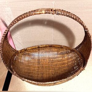 This vintage hand-woven rattan and reed basket with a handle and braided border